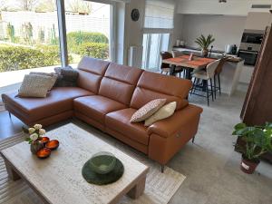 a living room with a brown leather couch and a table at Aurelia in Ronse