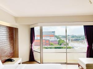 a bedroom with a large window with a view at Ayothaya Riverside Hotel in Phra Nakhon Si Ayutthaya