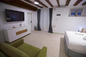 a bedroom with a bed and a tv and a couch at Apartments Lara 2 with more affordable parking in Piran