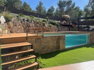 een zwembad in een tuin met een trap en een rotswand bij Villa Vicente in Canyelles