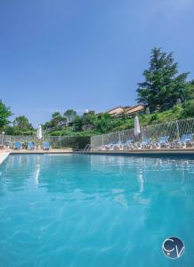 a large blue swimming pool with chairs and umbrellas at St-Germain - Les Terrasses de l'Ardèche - Piscine in Salavas