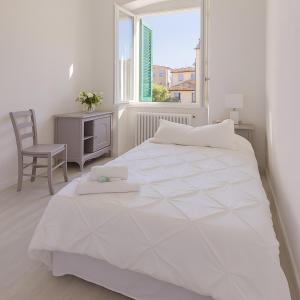 a white bedroom with a large white bed and a window at Chez Amèlie in La Spezia