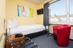 a hotel room with a bed and a red chair at Hotel Bären Suhr in Aarau