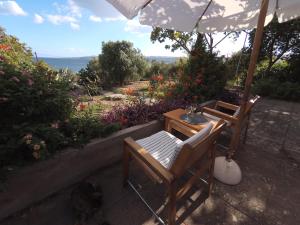 a patio with a table and chairs and an umbrella at Εξοχικό σπίτι σε κτήμα δίπλα στη θάλασσα in Mantamádos
