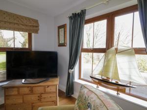 a living room with a tv and a boat on a dresser at Clondallon Cottage in Rathmullan