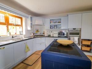 a large kitchen with white cabinets and a blue island at Clondallon Cottage in Rathmullan +34 photos