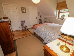 a bedroom with a bed and a lamp on a table at Clondallon Cottage in Rathmullan