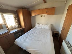 ein kleines Schlafzimmer mit einem weißen Bett darin in der Unterkunft Sherwood 307 - Golden Palm, ramped veranda, central heating, bed linen, WiFi - Meadow Lakes Caravan & Lodge Hire in Chapel Saint Leonards + 11 Fotos