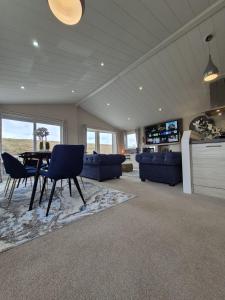 a large living room with a table and blue chairs at The Blue Lagoon 2 bedroom lodge with hot tub in Walton-on-the-Naze