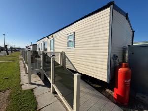 einem weißen Wohnwagen mit einem Hydranten neben einem Zaun in der Unterkunft Sherwood 307 - Golden Palm, ramped veranda, central heating, bed linen, WiFi - Meadow Lakes Caravan & Lodge Hire in Chapel Saint Leonards