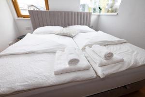 Una cama blanca con toallas encima. en Riedwohnung 1- Lustenau, en Lustenau 12 fotos más