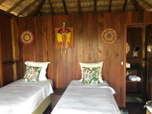 two beds in a room with wooden walls at Ventos do Delta Kite Chalés in Tutóia