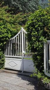 a white gate in a hedge with a bush at Casa Verde in Santa Maria Maggiore