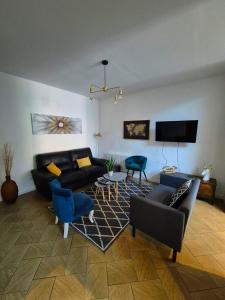 a living room with a black couch and blue chairs at Le Repère - Maison 5 Chambres proche Vieux Lille in Tourcoing