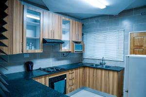 a kitchen with wooden cabinets and a black counter top at Same Stay Inn in Francistown