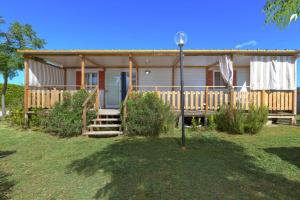 a house with a porch and stairs to it at Camping Village Tuscia Tirrenica in Tarquinia