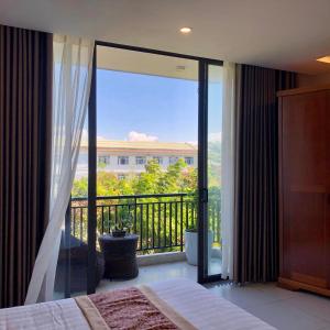 een slaapkamer met uitzicht op een balkon bij Son Tra Green Hotel & Apartment in Da Nang
