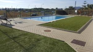 a swimming pool with a bench in the grass at Casa Roc de Sant Gaietà in Comarruga