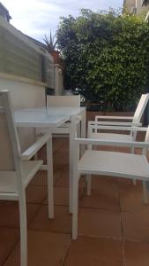 two white picnic tables and chairs on a patio at Casa Roc de Sant Gaietà in Comarruga