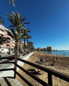 a beach with palm trees and people on the sand at Los Molinos in Torrevieja