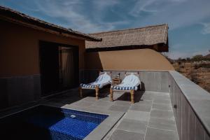 a patio with two chairs and a swimming pool at The Foothills Escape in Pushkar