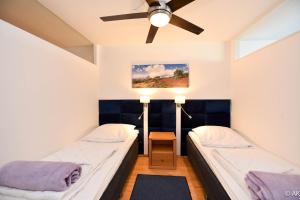 two beds in a room with a ceiling fan at Haus "Panorama" Appartement PAN087 in Duhnen +25 photos