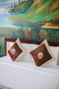 a bed with two pillows on it with a painting at Đoàn An điều dưỡng 198 in Xuan An