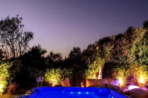 a garden with chairs and lights at night at Cyan Villa in Anavyssos