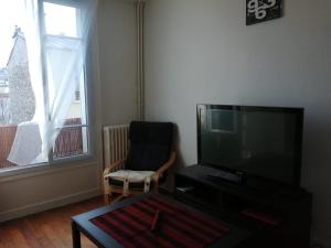 a living room with a flat screen tv and a chair at Chez Sophie, cosy et calme, à deux pas de Paris in Saint-Mandé