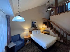 a bedroom with a bed and a blue chair at Promenade Inn & Suites Oceanfront in Seaside
