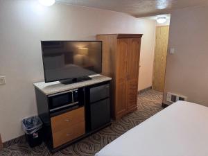 a hotel room with a flat screen tv and a bed at Promenade Inn & Suites Oceanfront in Seaside