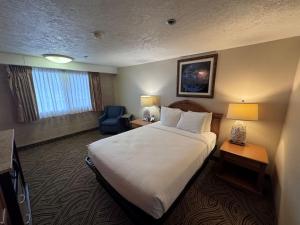 a hotel room with a bed and a chair at Promenade Inn & Suites Oceanfront in Seaside