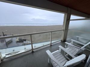 a balcony with two chairs and a view of the beach at Promenade Inn & Suites Oceanfront in Seaside
