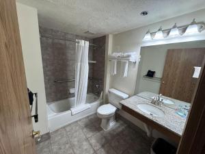 a bathroom with a toilet and a sink and a tub at Promenade Inn & Suites Oceanfront in Seaside