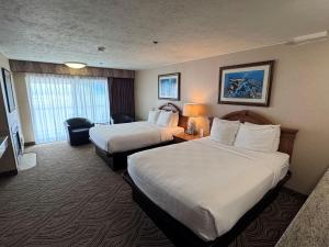 a hotel room with two beds and a desk at Promenade Inn & Suites Oceanfront in Seaside