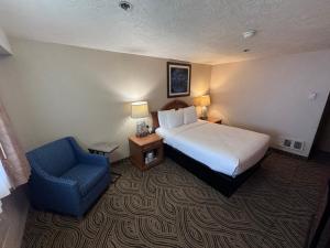 a hotel room with a bed and a blue chair at Promenade Inn & Suites Oceanfront in Seaside