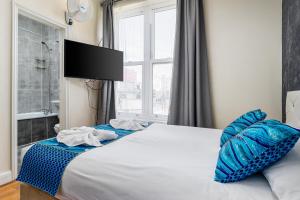 a bedroom with a bed with blue pillows and a window at Camden Apartments in London