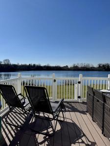 two chairs sitting on a deck overlooking the water at Robin's Nest - Cotswold Lakeside Lodge - Spring Lake in South Cerney
