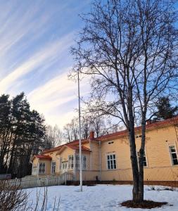 a house with a tree in the snow at Pappilan Kartano in Kuopio