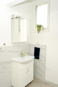une salle de bain blanche avec un lavabo et un miroir dans l'établissement Apartman Leo Jajce, à Jajce