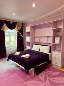 a bedroom with a purple bed with towels on it at Apartments Provence in Chernivtsi
