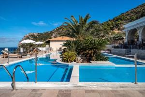a pool with palm trees and the ocean in the background at Sunset Premium Studio 12 in Agios Nikitas +21 photos