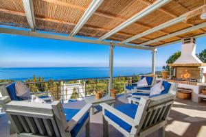 a patio with chairs and a table with a view of the ocean at Villa Thea by Villa Plus in Skinária