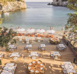 a restaurant on the beach with tables and umbrellas at Aragosta Suites in Paleokastritsa