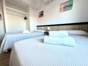 a hotel room with two beds with white sheets at Apartamento Velázquez Aeropuerto B in Málaga