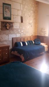 a bedroom with a blue bed and a brick wall at LOGÉVEIL - Maison d'hôtes ''Charme et Bien-être'' - proche forêt et golf in Baugé-en-Anjou