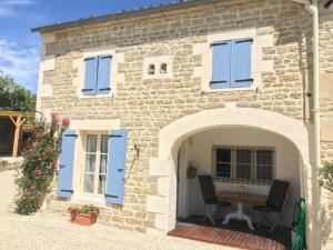 una casa in pietra con persiane blu e un tavolo all'esterno di Les Deux Marronniers Bataille a Saint-Georges-de-Longuepierre Altre 6 foto