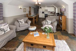 a living room with couches and a table and a kitchen at Coo Shed in Glenshee