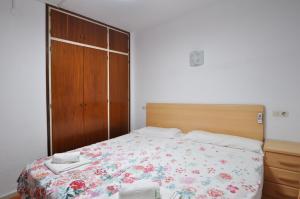 una camera da letto con un letto con copriletto floreale e un armadio in legno di Apartment Doble-4CD a Lloret de Mar