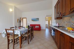 uma cozinha com uma mesa e algumas cadeiras e um quarto em Il giardino di Marina em Teulada